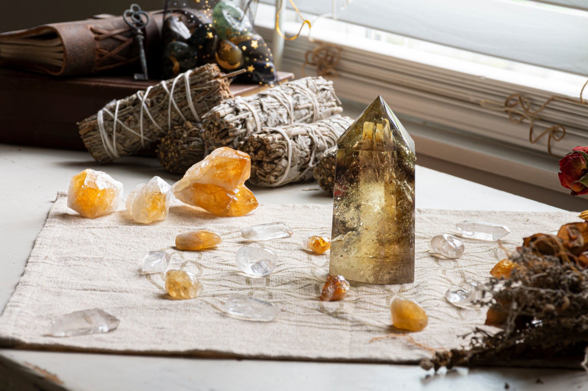 A top view image of a beautiful crystal healing grid with garden quarts and citrine crystal mixed with white sage smudge sticks and roses.
